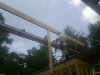 Carpenter setting a ridge beam over a new addition frame — Ice Dam Removal by Roofing Brothers in Queen