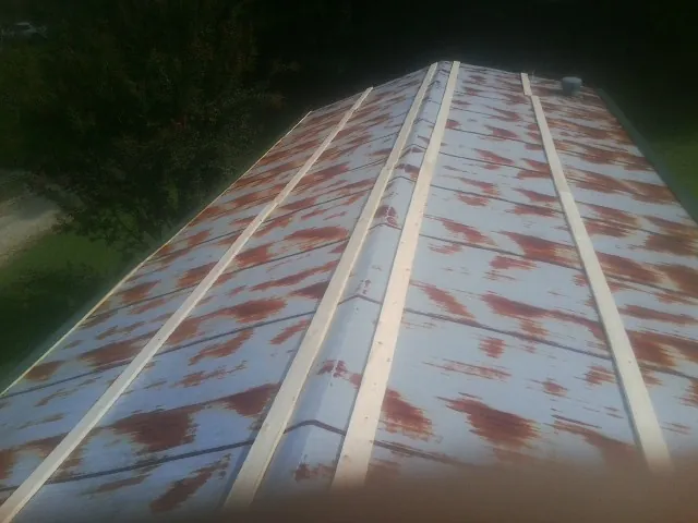 Rusted metal roof panels with new wood purlins before replacement — Storm Damage Roof Repair in Queen by Roofing Brothers
