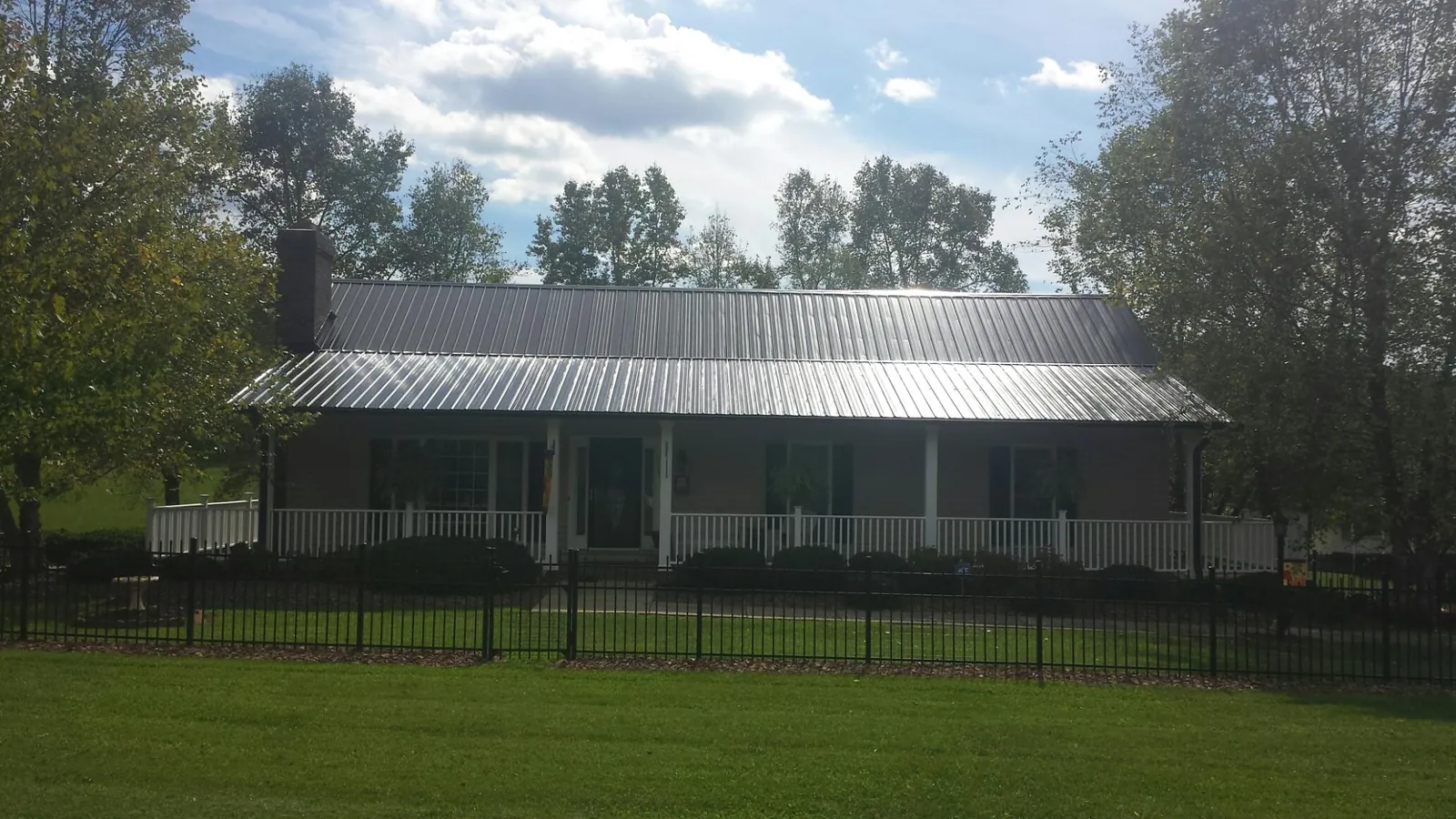 Gray metal roof on a brick ranch with a full width front porch — Gutter Guard Installation work by our crew in Queen