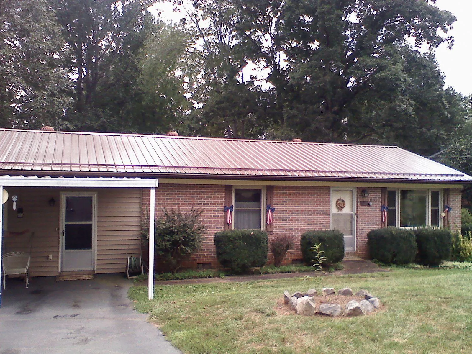 Bronze metal roof and carport on a brick ranch home — Roof Repair work by our crew in Queen
